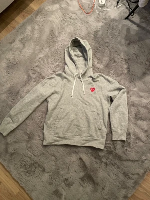 Grå hoodie Comme des Garçons Play - Grå hoodie från Comme des Garçons Play med vita platta snören. I extremt bra skick inga defekter alls i storlek s hör av er med vid frågor, pris, byten eller fler bilder 