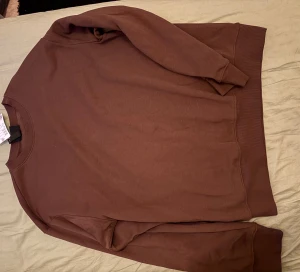 Vinröd loose fit sweatshirt från H&M - Säljer en brun sweatshirt från H&M i loose fit-modell. Tröjan har rund hals, långa ärmar och ribbade muddar vid hals, ärmslut och nederkant. Materialet är mjuk bomull som känns skönt mot huden. Perfekt för chill dagar och enkel att matcha med jeans eller joggers.