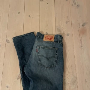 Levi's 511  - Snygga blå Levi's 511 jeans med klassisk femficksdesign. Jeansen har en något tvättad look och är tillverkade i slitstarkt denim med den ikoniska läderpatchen bak i midjan. Storlek W32 L34. Hör av dig frågor eller funderingar! Jeansen har ett litet hål vid knäet 