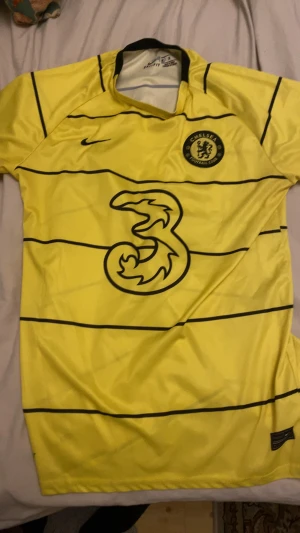 Chelsea FC matchtröja  - Chelsea FC matchtröja i gul med svarta horisontella ränder, Nike-logga och klubbmärke på bröstet. Nummer 29 och namnet Havertz på ryggen. Tillverkad i lätt polyester som andas, perfekt för fotboll eller att representera ditt lag.