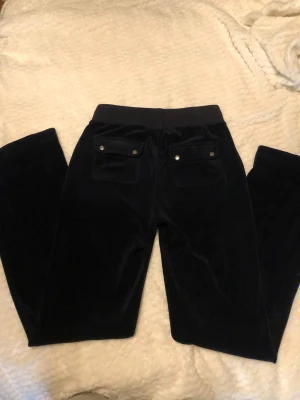 Mörkblå velourbyxor Juicy Couture XS - Snygga mörkblå velourbyxor från Juicy Couture i storlek XS. Väldigt bekväma. Säljer för att dom inte har kommit till användning. Byxorna är långa och har innerbenslängden 90cm typ. 💙