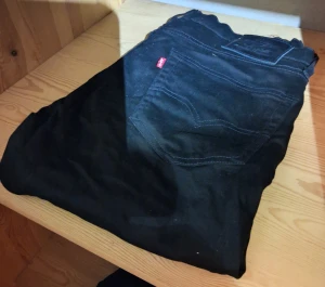 Svarta Levi's 501 jeans  - Svarta Levi's 501 jeans med klassisk femficksdesign och röd Levi's-tag på bakfickan. Jeansen har rak passform och är tillverkade i slitstarkt bomullsmaterial. Perfekt för dig som gillar tidlös stil och vill ha ett par jeans som funkar till allt.