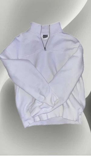 Vit half zip sweatshirt från Pull&Bear - Vit sweatshirt från Pull&Bear med half zip-dragkedja och hög krage. Tröjan har långärmade muddar och är gjord i mjuk bomullsmix som är perfekt för chill dagar. Enkel och clean design utan mönster, passar dig som gillar stilrena plagg.