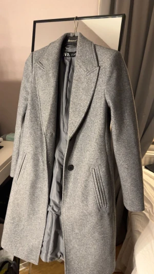 Kappa från Zara  - Säljer min kappa från Zara som endast är använd en gång alltså i nyskick. Kappan är figursydd utan band men med knappar som detaljer i ärmarna och där framme som går att knäppa, den har även en slits där bak. Hör av er vid fler frågor💗
