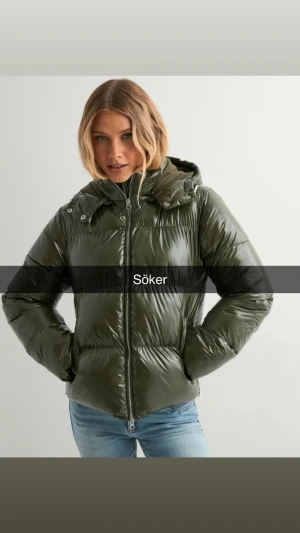 SÖKER denna jacka från Nelly storlek XS - Snygg mörkgrön pufferjacka med glansig finish och vadderade sektioner. Jackan har en stor huva med tryckknappar, hel dragkedja framtill och två sidofickor. Passformen är normal och jackan är perfekt för kalla dagar.