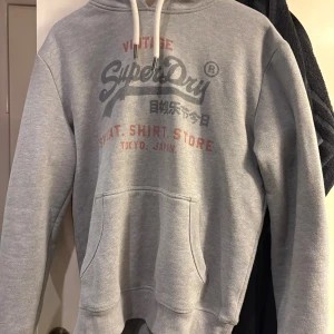 Grå hoodie från superdry - Säljer denna feta hoodie. Hoodien är i ett bra skick och är i storlek L. Nypris ca 900