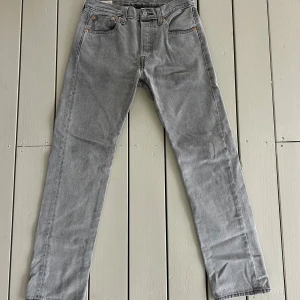 Grå Levis 501 jeans straight fit - Snygga grå Levis 501 jeans med klassisk rak passform och fem fickor. Jeansen har en tidlös look med knappgylf och är tillverkade i mjukt denimtyg. Perfekta för dig som gillar en clean och enkel stil.