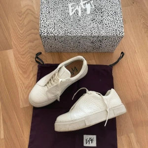 Vita sneakers från Eytys med lila detalj - Säljer ett par chunky vita sneakers från Eytys med lila band på hälen och grov platt sula.  Box och dustbag medföljer.