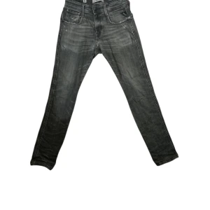 Replay grå slim jeans med slitningar - Snygga grå jeans från Replay i slim fit med slitna detaljer och lätt tvättad look. Klassisk femficksmodell med Replay-logga på fickan och coola sömmar på bakfickorna. Säljer billigt då dem har lagningar vid skrevet. Perfekta för dig som gillar en streetig och trendig stil. Går ner i pris vid snabb affär