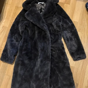 Mörkgrå pälsjacka från IVIVI - Säljer en lång, fluffig och lyxig mörkgrå pälsjacka från IVIVI. Jackan har bred krage, helfodrad insida och en oversized känsla. Perfekt för dig som vill sticka ut och hålla dig varm under kalla dagar.