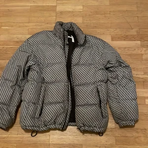 Mönstrad pufferjacka från Selected Homme - Säljer en svartvit pufferjacka från Selected Homme då den inte andvänds känge. Jackan har krage med en tunn luva som går att rulla ut och två fickor framtill. Fodrad med 3M Thinsulate för extra värme. Perfekt för kalla dagar och riktigt snygg streetstil. Den har storlek M men är väldigt stor och passar enkelt till L.