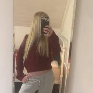 Vinröd stickad croppad tröja - Säljer en vinröd stickad tröja med v-ringad hals och croppad passform. Tröjan har långa ärmar och ribbade detaljer vid muddar och nederkant. Perfekt för dig som gillar en chill och snygg stil med lite edge. Den är ifrån HOLLISTER!