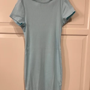 Ljusblå tight ribbad kortklänning - Söt ljusblå klänning från New Yorker i storlek L. Enkel och bekväm modell som sitter snyggt på kroppen. Använd ca 5 gånger men i mycket fint skick! Perfekt till vardag, skola eller sommardagar ☀️