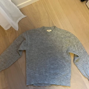 Grå stickad tröja från H&M - Säljer en enkel och snygg grå stickad tröja från H&M. Tröjan har rund hals, ribbade muddar och långärmad passform. Perfekt nu till hösten🍂💖