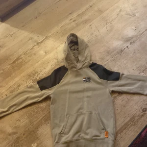 Beige hoodie ATHL WEAR från H&M - Snygg beige hoodie från H&M med svart detalj på axlarna och trycket ATHL WEAR framtill. Tröjan har huva, magficka och långa ärmar. Perfekt för chill eller sportig stil. Mjuk bomullskänsla och cool kontrast mellan färgerna.
