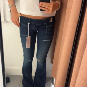 Mörkblå bootcut jeans med slitningar - Super snygga low waist bootcut jeans med slitningar💖slutsålda på hemsidan, storlek XS! Endast använda 2 gånger, inget tecken på användning💛