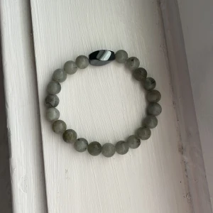 Grått pärlarmband med svart detalj - Stilrent armband med runda grå pärlor och en svart, blank detalj som bryter av snyggt. Perfekt för dig som gillar minimalistiska accessoarer med en cool twist. Passar både till jeans och hoodie eller när du vill addera något extra till din look.