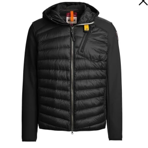 Svart pufferjacka från Parajumpers - Svart pufferjacka från Parajumpers med huva, dragkedja och en gul detalj vid halsen. Jackan har quiltad framsida, släta ärmar och en bröstficka med dragkedja. Perfekt för kyliga dagar och snygg streetstil.