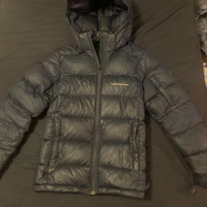 Mörkblå dunjacka Peak Performance - Mörkblå dunjacka från Peak performance. Modellen är frost down jacket i barnstorlek 160 men passar som en xs/s 💞på vänster arm finns en pytteliten defekt (se bild)  men inget som märks. Nypris är 2700 !