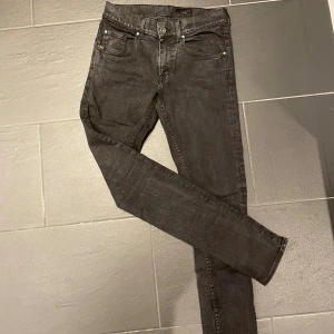 Svarta slim jeans Tiger of Sweden - Säljer ett par riktigt feta Svarta slim fit jeans från Tiger of Sweden i modellen Blackend. Jeansen har klassisk femficksdesign, smal passform och är tillverkade i ett stretchigt jeanstyg. Snygga detaljer med svarta sömmar och metallknapp framtill. Kontakta vid frågor!