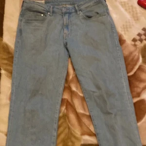 Ljusblå regular fit jeans från H&M - Säljer ett par ljusblå regular fit jeans från H&M. Klassisk femficksmodell med raka ben och normal passform. Jeansen är tillverkade i bomull och har en enkel, stilren look som passar till det mesta.