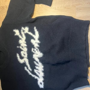 Svart stickad tröja med vit text - As fet Saint Laurent tröja, storlek M som jag fick i julklapp fast kom aldrig riktigt till användning. Pris går att diskutera 