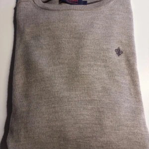 Beige merinoulltröja från Morris - Snygg beige stickad tröja från Morris i 100% merinoull. Klassisk rund hals och diskret Morris-logga broderad på bröstet. Långärmad modell med ribbade muddar och mjuk känsla, perfekt för lager-på-lager under höst och vinter. Använd ett fåtal gånger. Tvättad en gång  Storlek M men krypte lite vid tvätt. Så mer som en st S