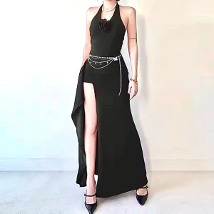 Svart långklänning med slits och halterneck + present ( midja kedja i bilden) - Supersnygg svart långklänning med halterneck och djup slits framtill. Klänningen har en tight passform och en dekorativ blomdetalj vid bysten. Perfekt för dig som vill sticka ut med en elegant och modern look.