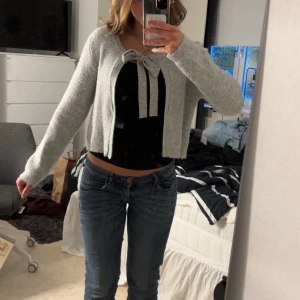 Ljusgrå stickad kofta med knyt från J'aime - Superfin ljusgrå stickad kofta från J'aime OLYTO. Långa ärmar och söt knytning framtill. 