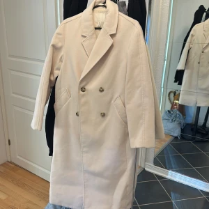 Beige kappa från H&M med knappar - Vit kappa, det är storlek XS men är stor i storleken så passar lätt en S/M