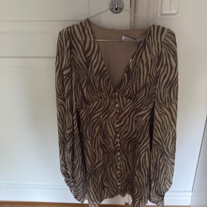 Zebramönstrad Florence Mini Dress från Adoore - Snygg kortklänning från Adoore med zebramönster i beige och brunt. Ny med prislapp nytt pris 1495kr
