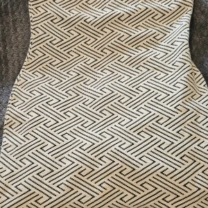 Vit och svart mönstrad kortkjol - Snygg kortkjol med grafiskt svartvitt mönster och strukturerad yta. Kjolen har en diskret slits framtill och dragkedja bak för enkel påklädning. Materialet känns tjockt och kvalitativt, perfekt för dig som gillar statement-plagg med coola detaljer.