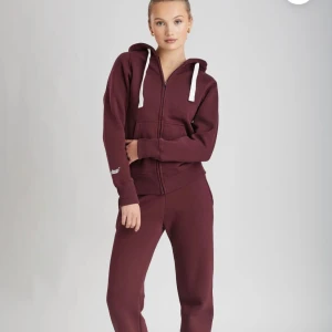 Vinröda mjukisbyxor med relaxed fit - Snygga vinröda mjukisbyxor med normal passform och resår i midjan. Byxorna är tillverkade i mjuk bomull och har en enkel, stilren look utan synliga detaljer. Perfekta för chill dagar eller när du vill vara bekväm.