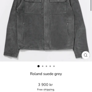 Grå suede jacka från Roland - Brand new, never worn — still in perfect condition. Premium soft goat suede in a stylish grey color. Lightweight, luxurious feel, and timeless design. Features two chest pockets, hidden zippers, and a minimal Scandinavian look. Original price: 3,900 kr  Condition: New, unused Size: XL Color: Grey Fit: Regular Shipping: Fast and well-packaged  Perfect for autumn or spring — sleek, versatile, and high-quality craftsmanship from Human Scales. 