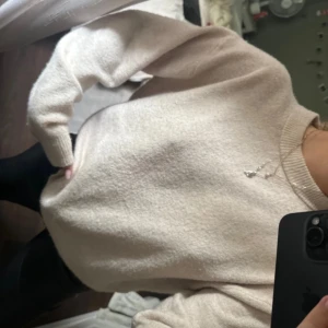 Beige stickad tröja med rund hals - Mysig beige stickad tröja med rund halsringning och långa ärmar. Tröjan har en relaxed fit och ribbade muddar vid ärmslut och nederkant. Perfekt för lager-på-lager och chill dagar.