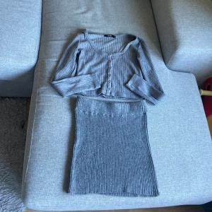 Grå ribbad klänning från Bik Bok - Supersnygg sett grå ribbad tröja från Bik Bok med långärmad överdel kjol från Gina tricot och knappdetaljer framtill. Klänningen är kort och har en figurnära passform som framhäver siluetten. Perfekt för dig som gillar stilrena och bekväma outfits.man kan även köpa bara en om man vill 