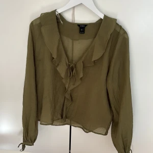 Olivgrön blus med volang från Lindex - Säljer en olivgrön blus från Lindex 