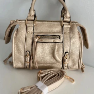 Guld/beige väska - Säljer min superfina, unika väska. Den är använd en gång och kommer utan defekter med ett längre band. Super rymlig och har fack innuti och utanpå🩷🩷
