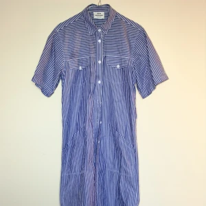 Skjortklänning  - Skjortliknande klänning från danska märket Mads Norgaard. Går till smalbenen på mig som är 160 cm lång. 2 knappar saknas längst ned.