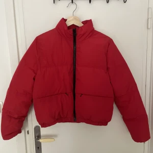 Röd jacka - En kortare röd pufferjacka från h&m i storlek S. Två fickor med gömd dragkedja på framsidan. Bra höst/vår-jacka.