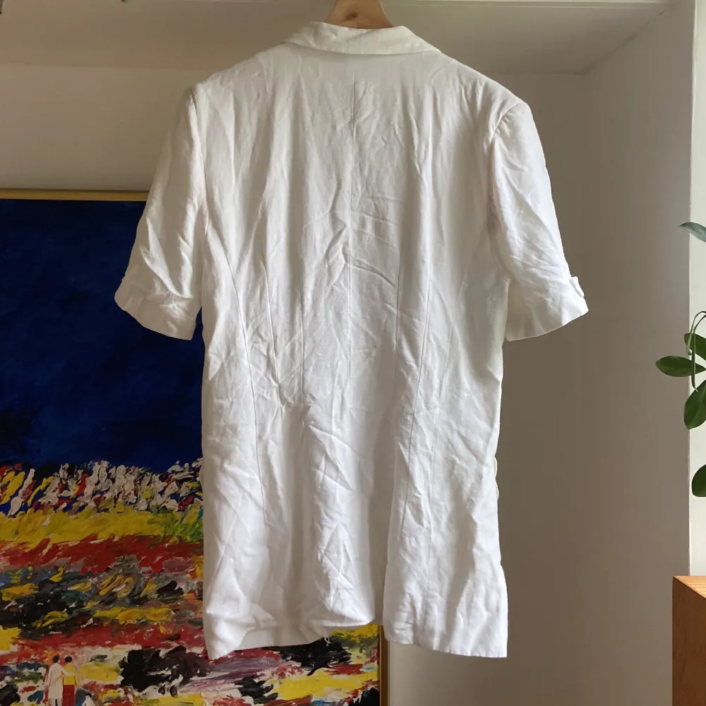 En vit längre kortarmad skjorta, en liten reva i sömmen i fodret (finns bild), annars i fint skick. Kostymer.