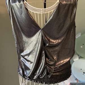 Svartmetallic festtopp - Sparsamt använd i storlek M. Djup rygg, riktigt läcker! Inköpt för flera år sedan. 