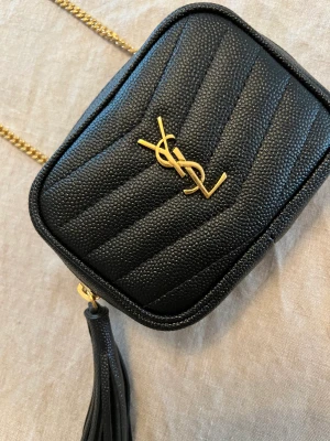 YSL Grain de Poudre Key Pouch on Chain - Jag säljer min svarta YSL monogram väska med en avtagbar axelrem i läder och kedja. Väskan är i 100% calfskin leather.    Dustbag, box och äkthetsbevis finns.  Väskan är helt i nyskick och endast använt ett fåtal gånger. Inga som helst anmärkningar. 