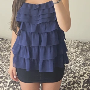 Mörkblå Volang topp - Jätte söt top men som tyvärr aldrig kommer till användning! Ett pyttelitet hål på en av volangerna men inget som märks. Köpt för 270kr säljer för 130kr.🥰 skriv om du har frågor!