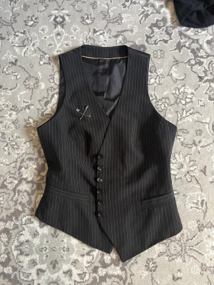 Svart kostymväst - Svart kostymväst i bra skick. Det går att justera midjan då det finns ett band där bak.  Köparen står för frakt.