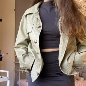 Grön skinnjacka - En av knapparna vid längst ner på armen har lossnat. Köpt från nakd för ca 700kr tror jag