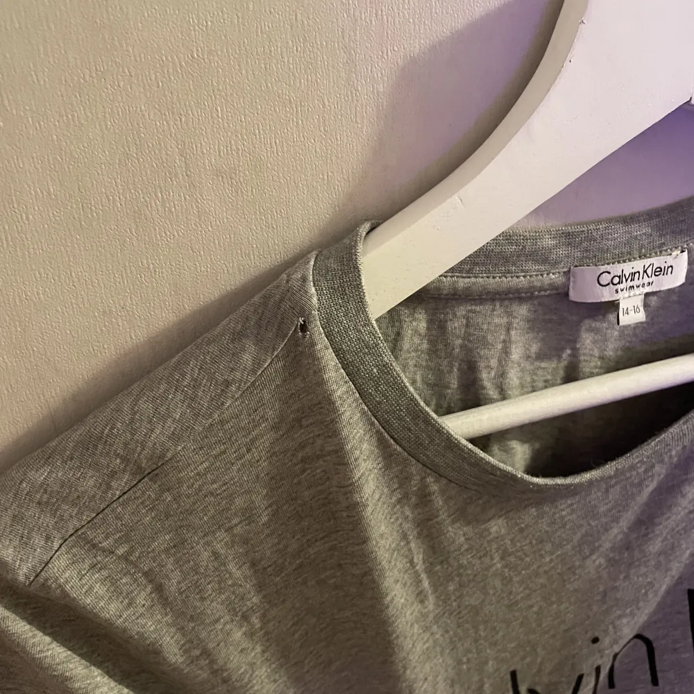 En grå Calvin Klein t-shirt med ett litet litet hål vid halsen. Storlek 14-16 men skulle säga M/S (bror på hur man vill att den ska sitta🥰). T-shirts.