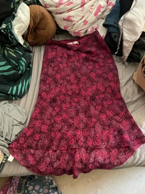 Kjol - Den har rosor på sig och är lila rosa vinröd 