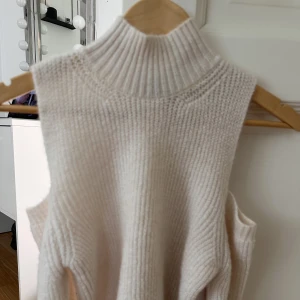 Stickad tröja  - Stickad tröja med hål i axlarna, aldrig använd 