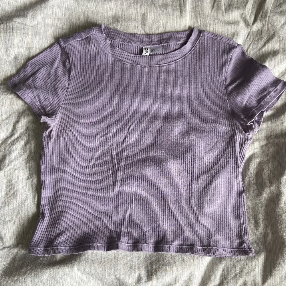 Tight, croppad T-shirt från HM divided i en kall lila färg. Köpt för 100 kr & säljer då jag ej använder. Material är tunt & ribbat. Använd kske 10 gånger.. T-shirts.